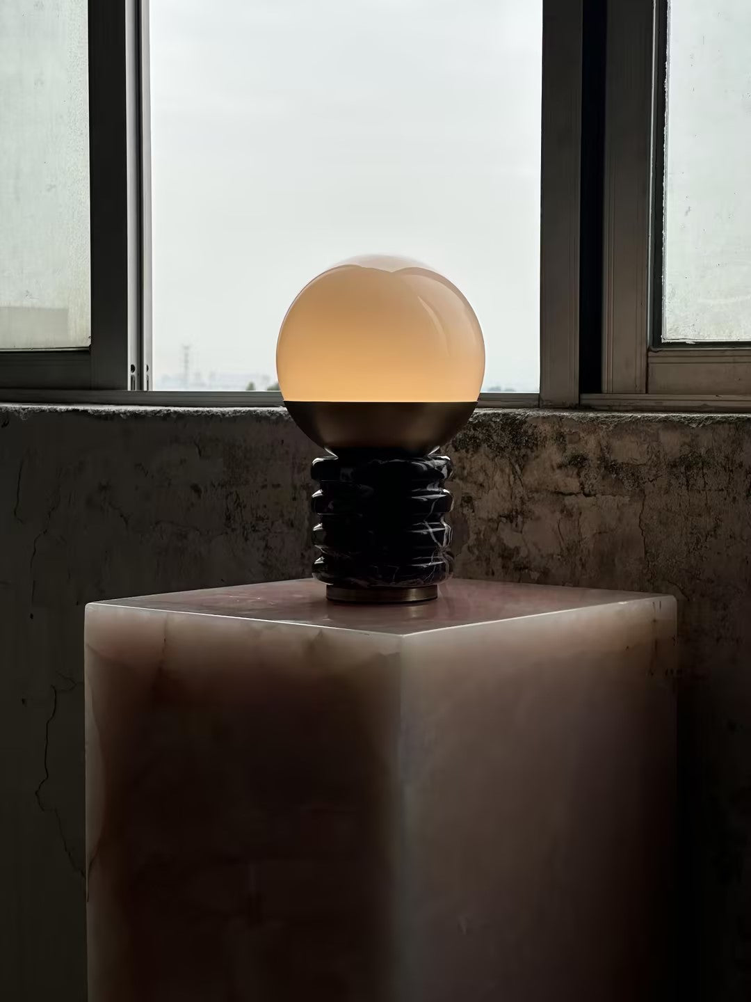 Lámpara de mesa de mármol Sferina – encendida sobre un pedestal