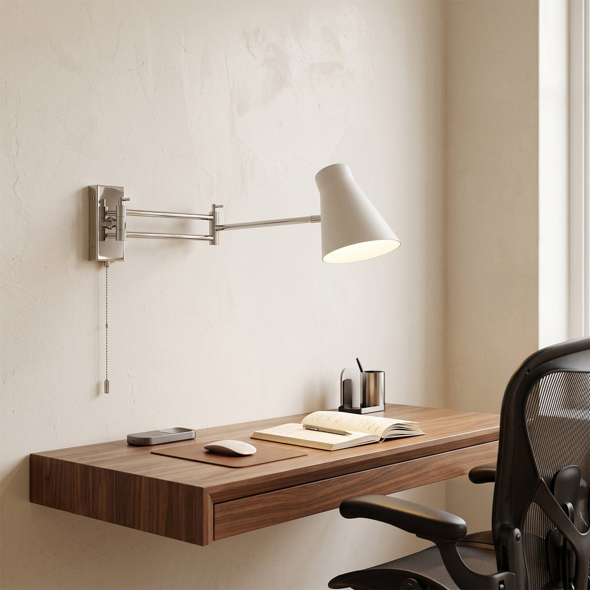 Aplique de pared con brazo extensible Kurela – pantalla blanca sobre un escritorio de madera