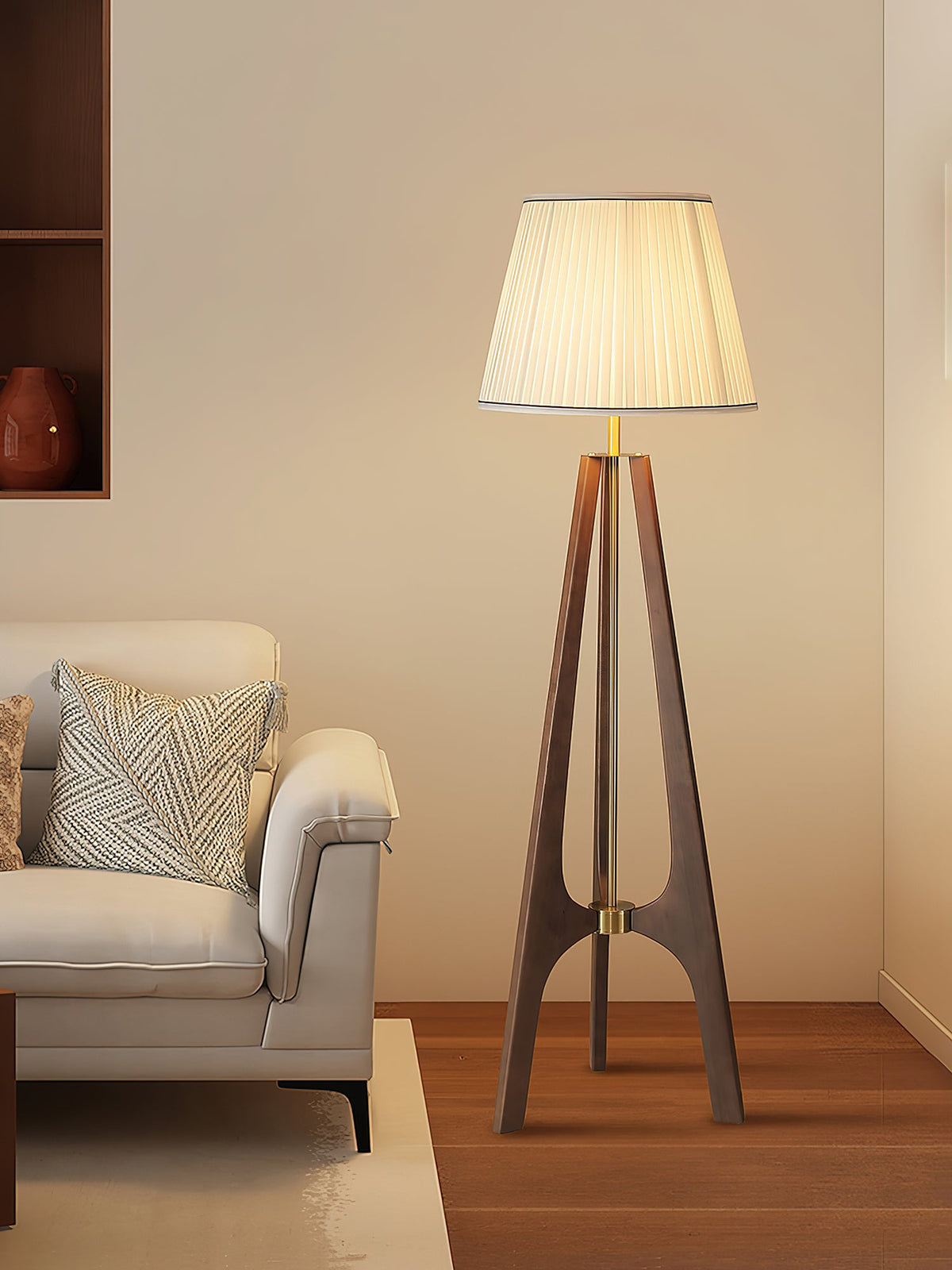 Lámpara de pie trípode de madera con pantalla plisada blanca Sabina – en un rincón junto a un sofá gris