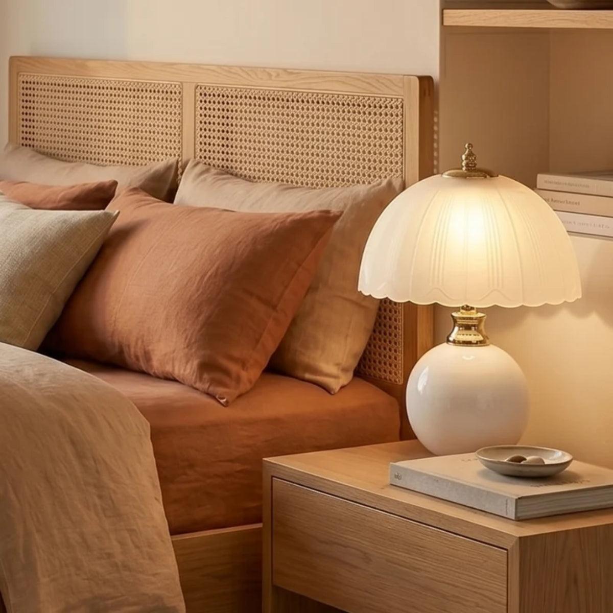 Lámpara de mesita de noche Rizonda – con base blanca junto a una cama de ratán