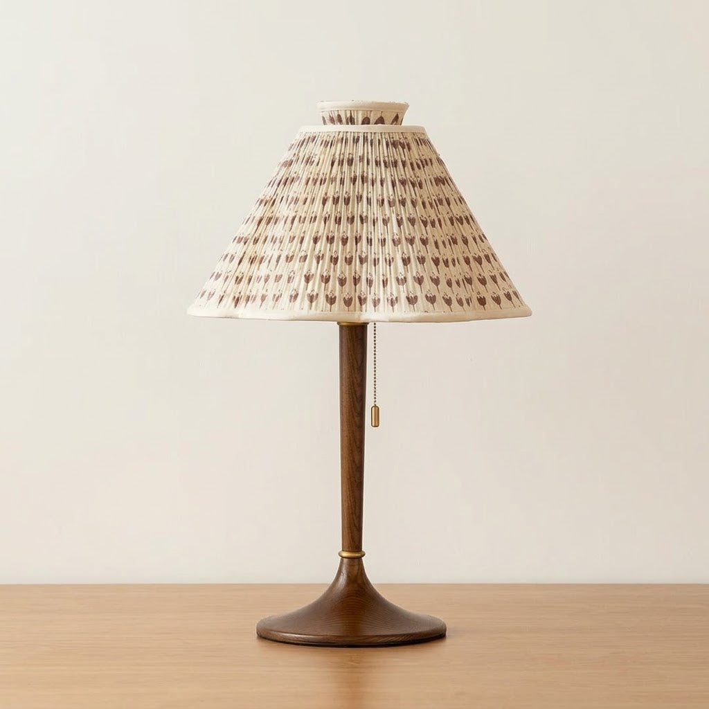 Lámpara de mesa plisada Tulipela – sobre una mesa de madera