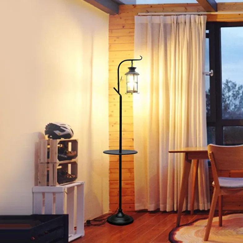 Lámpara de pie estilo farol negra Ormina – con bandeja, junto a una ventana