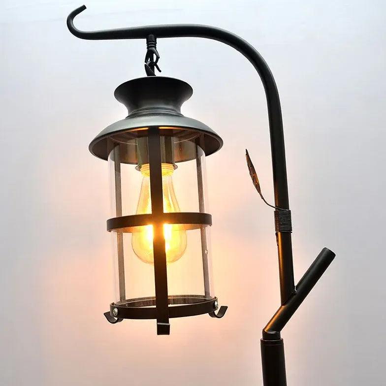 Lámpara de pie estilo farol negra Ormina – detalle del farol de cristal con bombilla encendida