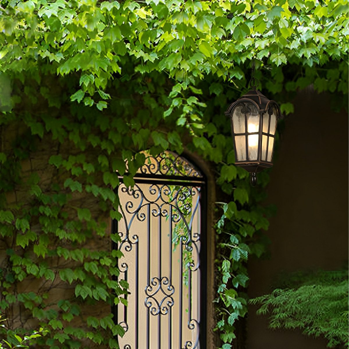 Lámpara colgante de exterior Ilvera – junto a una puerta de forja con hiedra