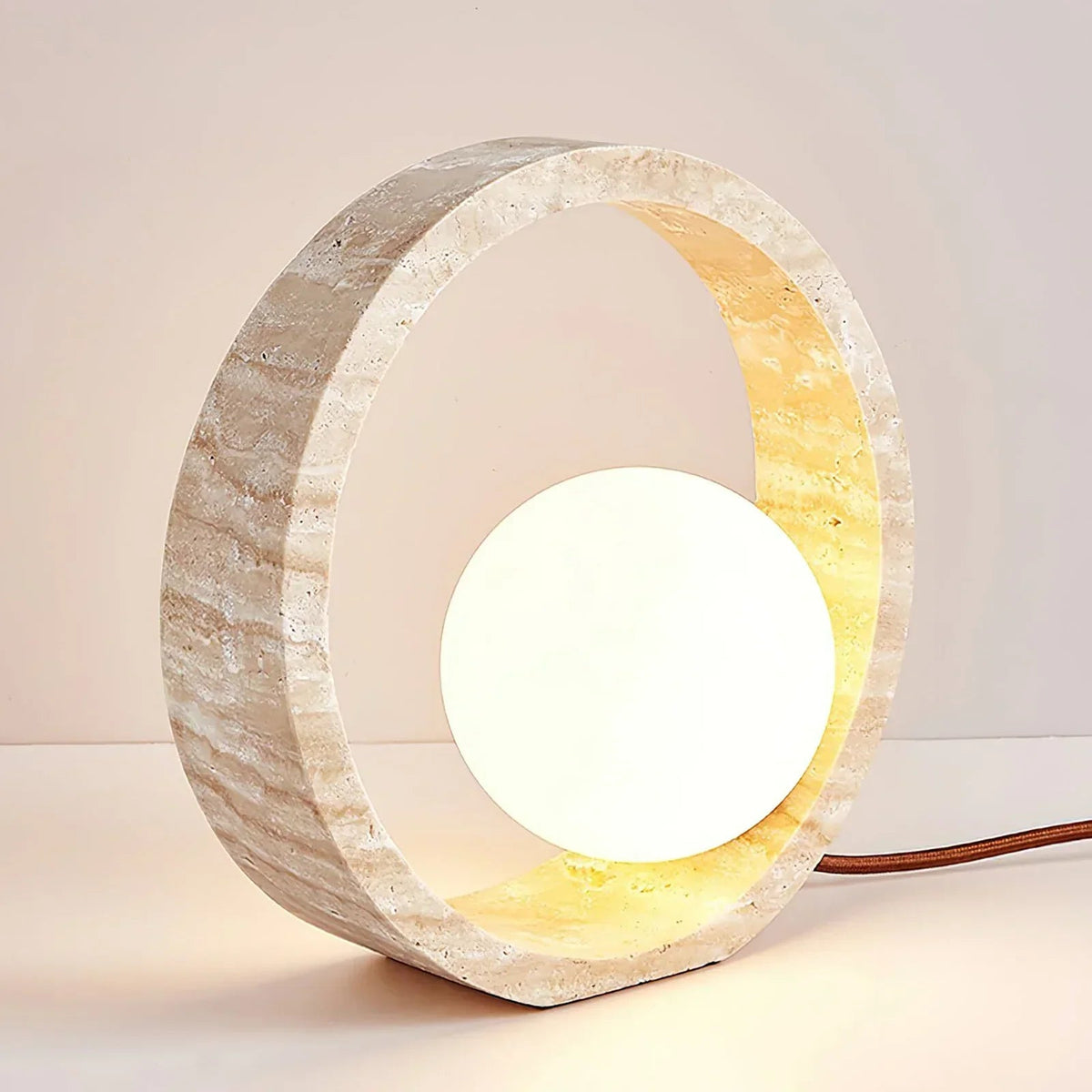 Lámpara de mesa de travertino Anella – encendida de frente con la esfera iluminada