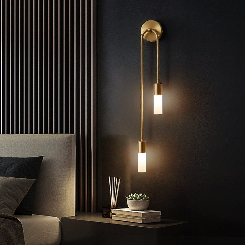 Aplique de pared LED dorado Hilara junto a un cabecero – imagen 2