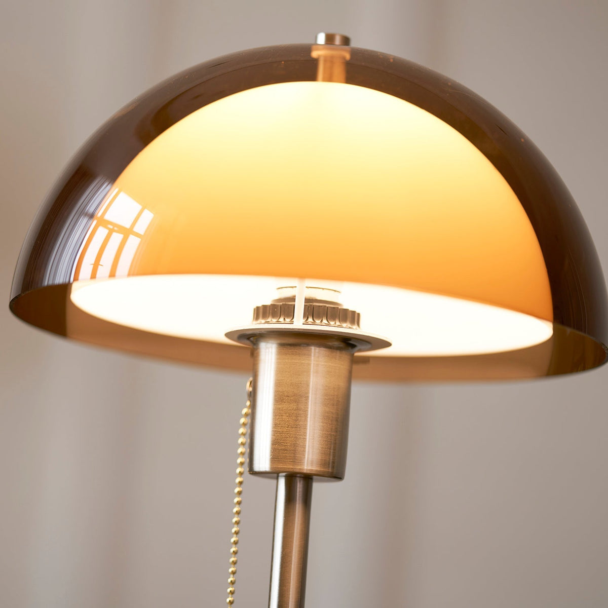 Lámpara de mesa retro Fambra – interior de la cúpula ámbar encendida