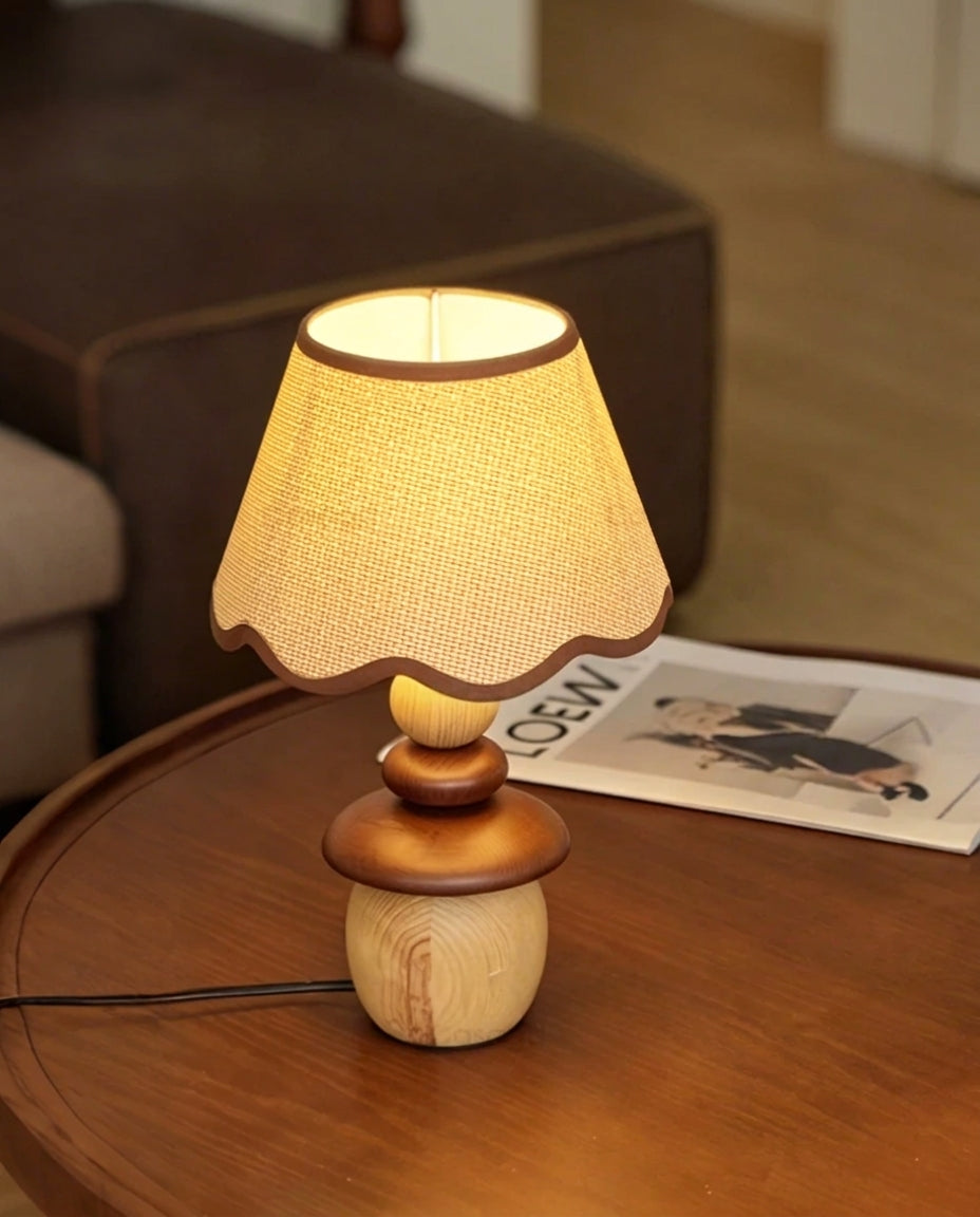 Lámpara de mesa de madera Frenela – encendida junto a un sofá de terciopelo marrón