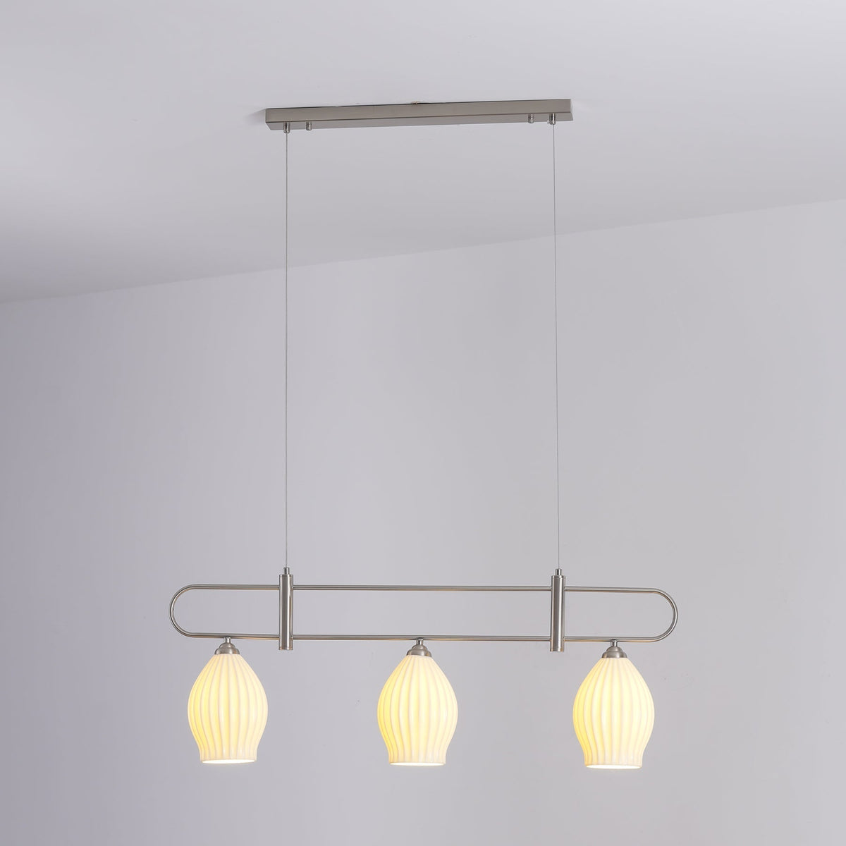 Lámpara colgante lineal de cerámica Gajela – níquel de tres luces encendida