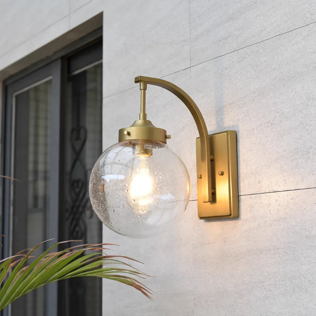 Aplique de pared exterior Ozela – en dorado junto a una puerta