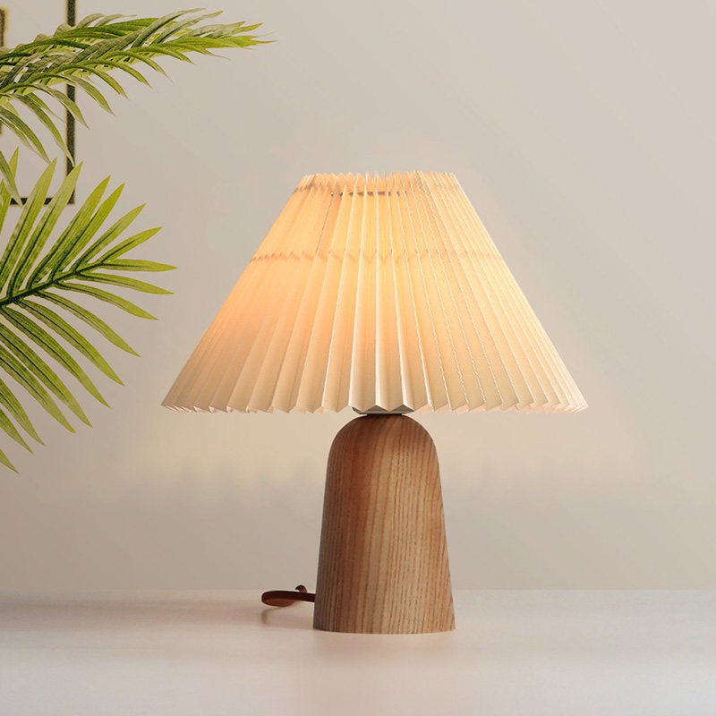 Lámpara de mesa con pantalla plisada Hilveta sobre una mesa auxiliar de madera – imagen 5