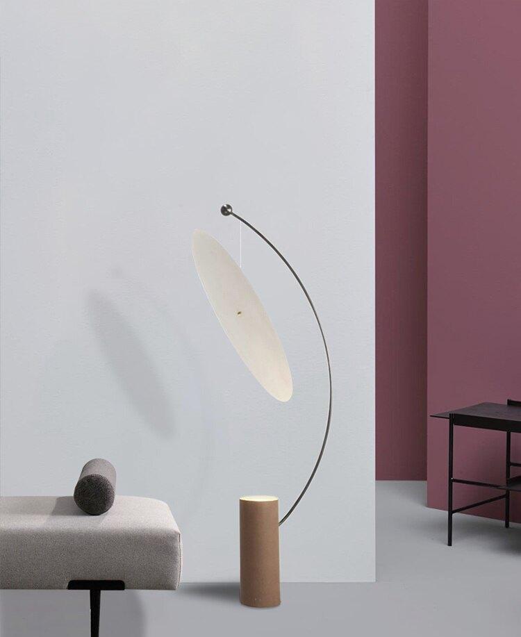 Lámpara de pie de arco con disco reflector Velune – junto a un banco tapizado