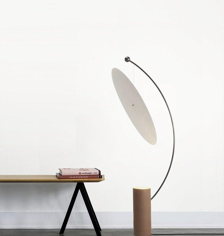 Lámpara de pie de arco con disco reflector Velune – junto a un banco de madera