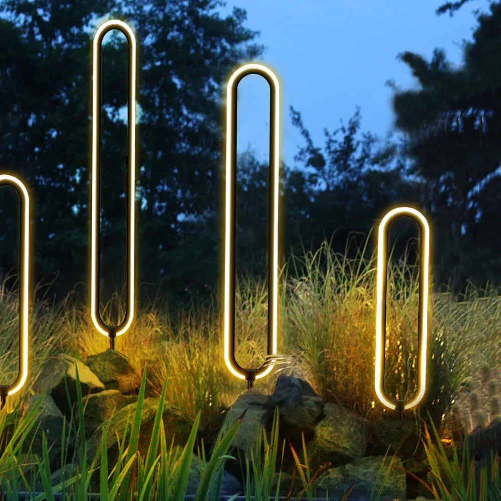 Baliza de jardín LED Iolana – varias balizas encendidas entre gramíneas