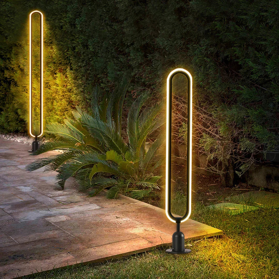 Baliza de jardín LED Iolana – encendida junto a un camino de piedra