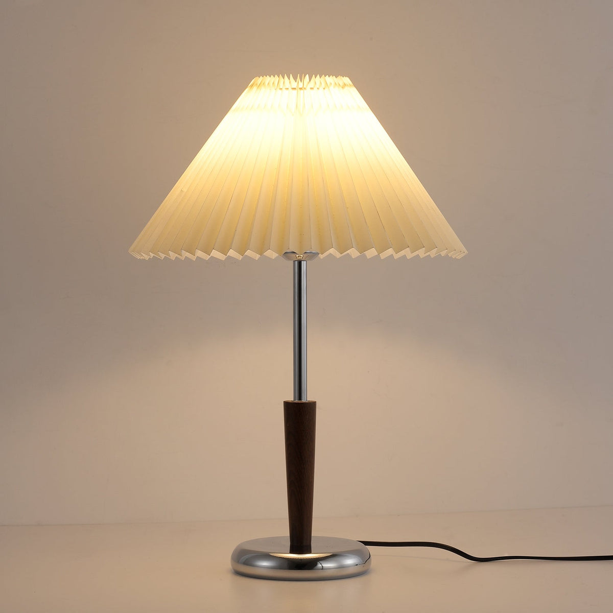 Lámpara de mesa con pantalla plisada Ivenna – vista en ángulo sobre fondo neutro