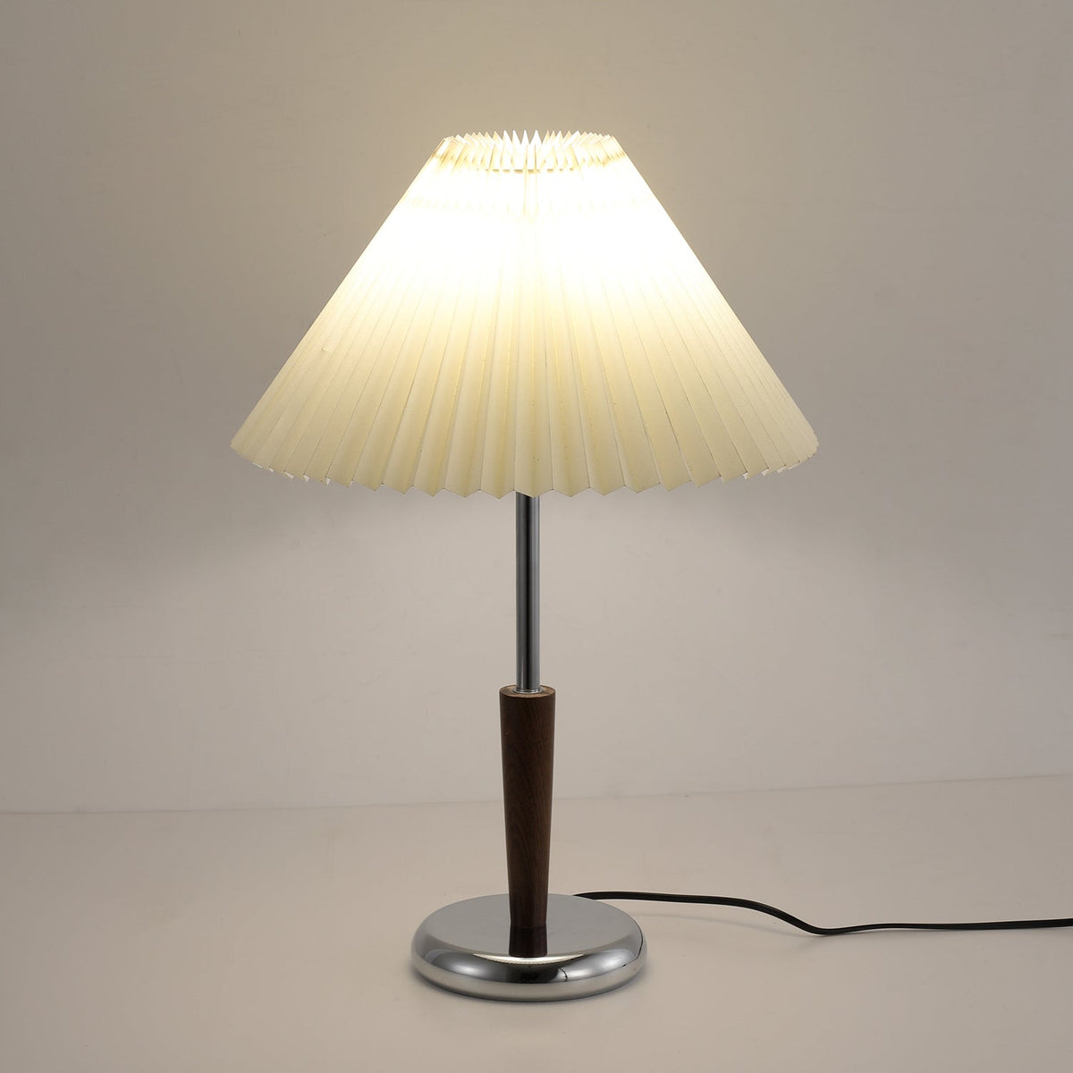 Lámpara de mesa con pantalla plisada Ivenna – encendida en ambiente cálido de tarde