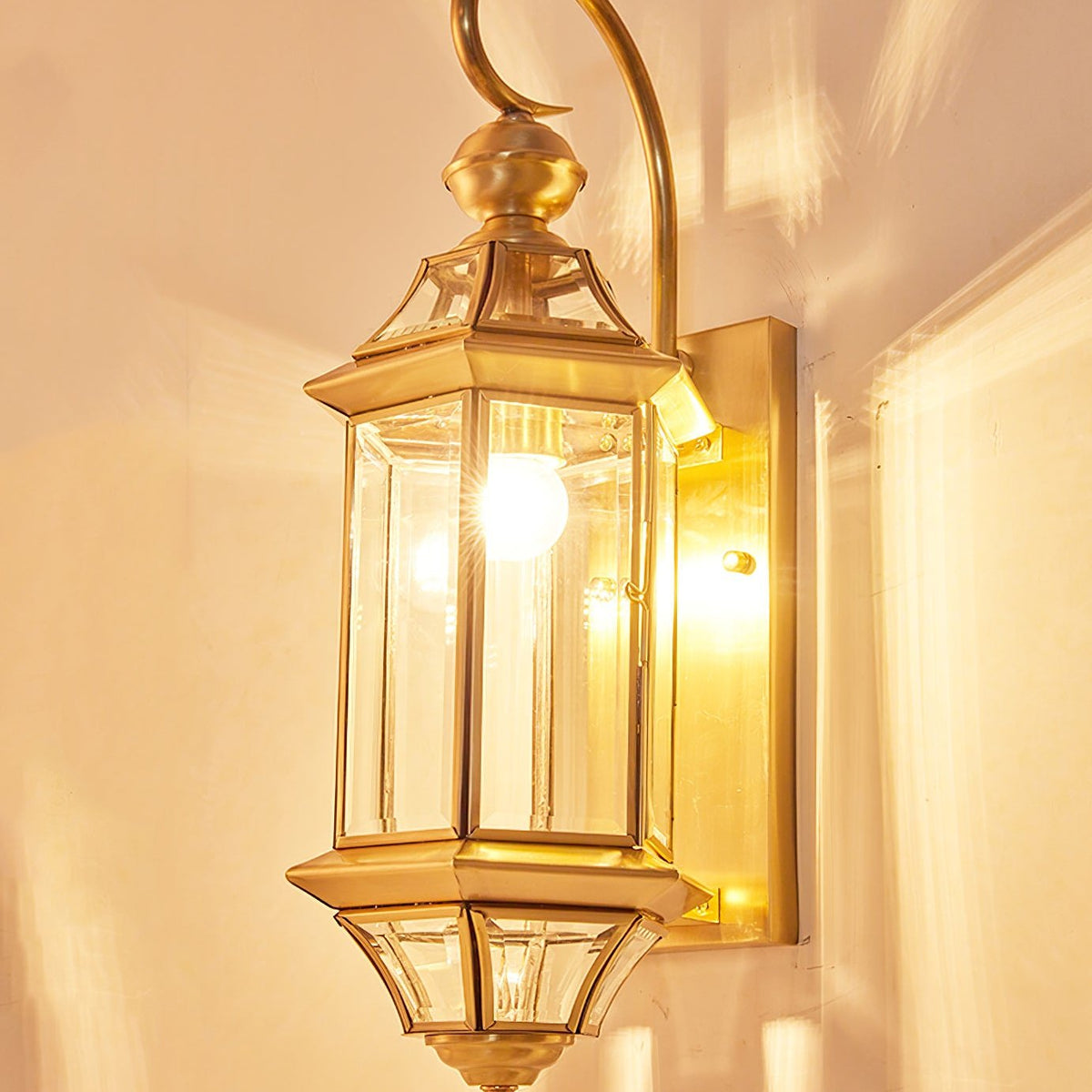 Farol de pared exterior de latón Jaroda – encendido sobre pared cálida
