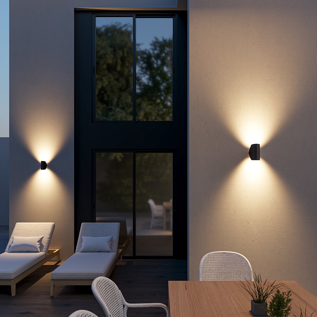 Aplique de pared orientable Jovira – negro en la fachada de un patio de noche