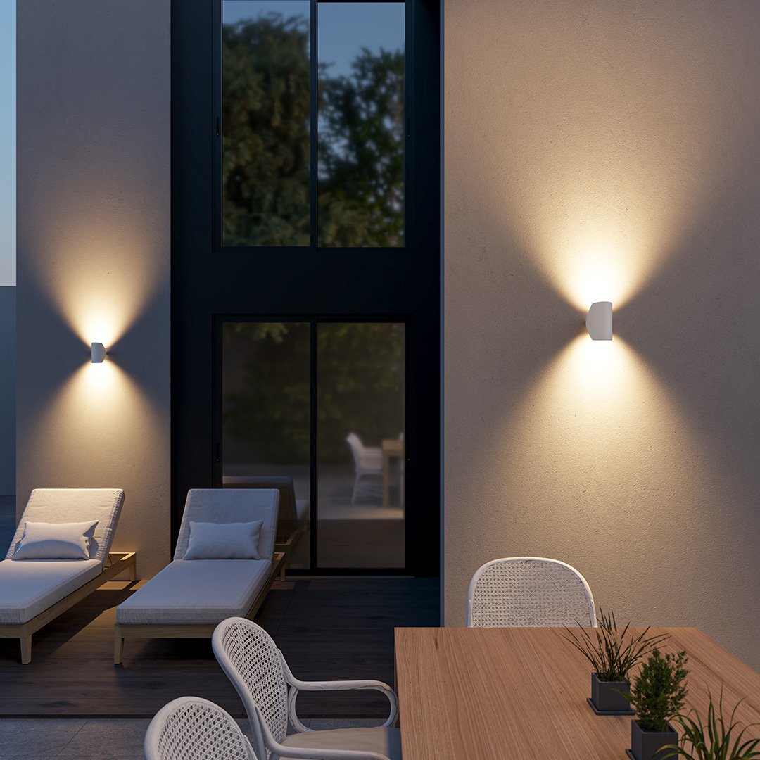 Aplique de pared orientable Jovira – blanco en la fachada de un patio de noche