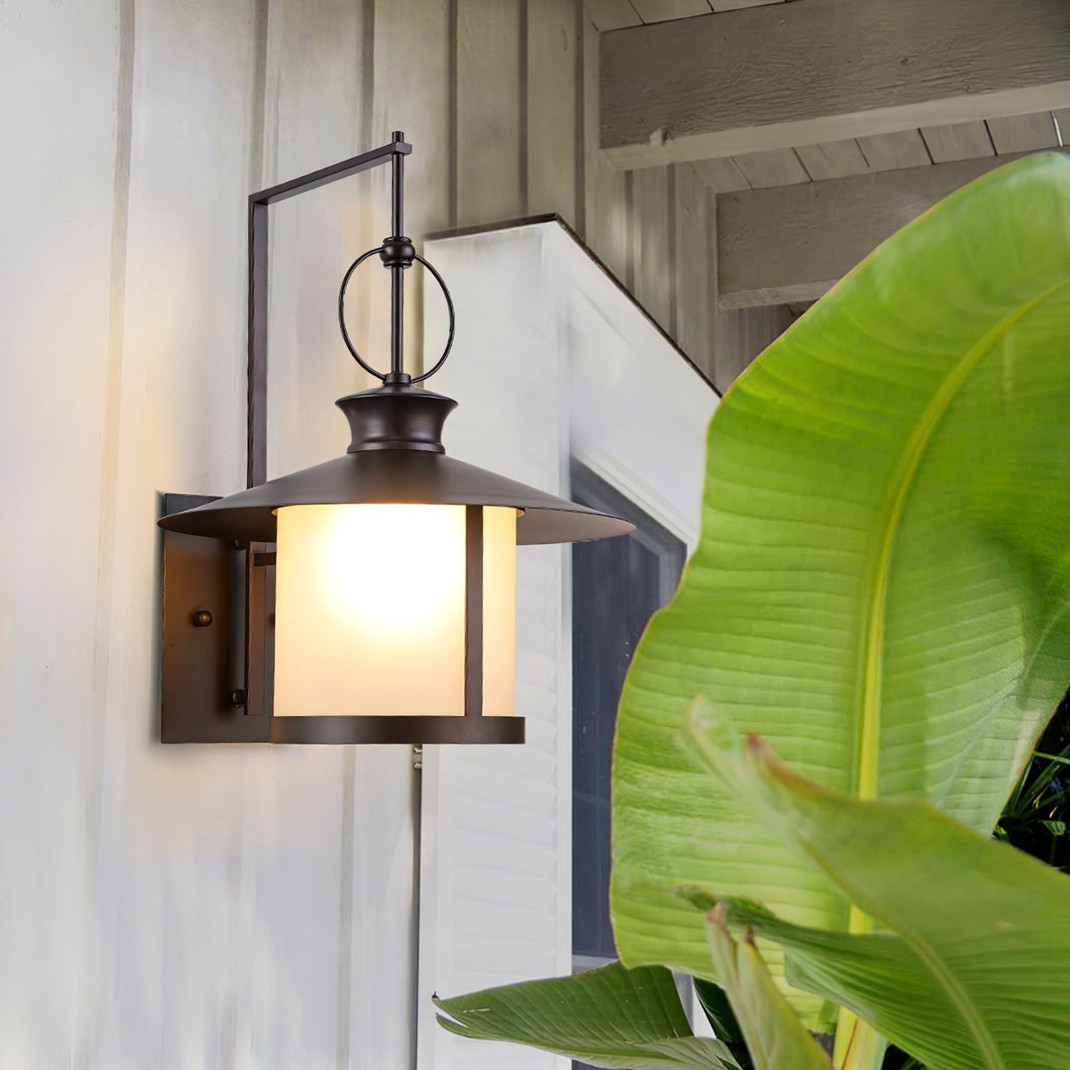 Aplique de pared exterior Jucela – junto a una planta tropical