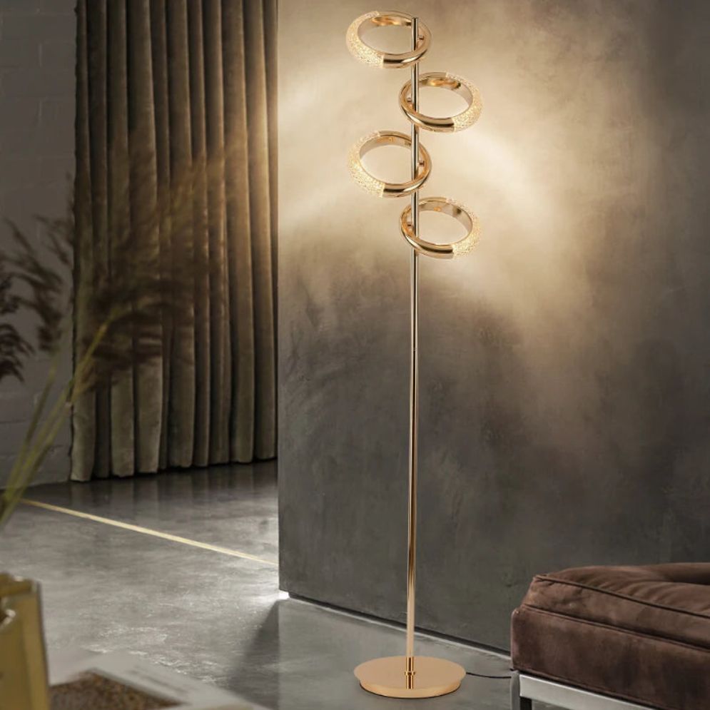Lámpara de pie LED con anillos dorados Sortiva – encendida junto a una cortina