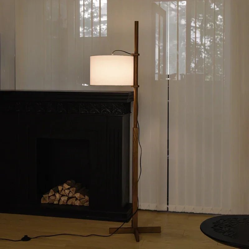 Lámpara de pie de madera Rasela – con luz neutra junto a una chimenea
