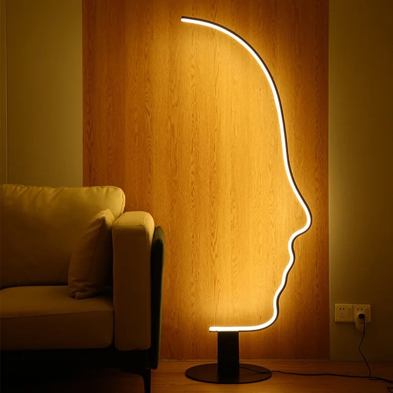Lámpara de pie LED con silueta de rostro Quiara – con luz cálida sobre pared de madera