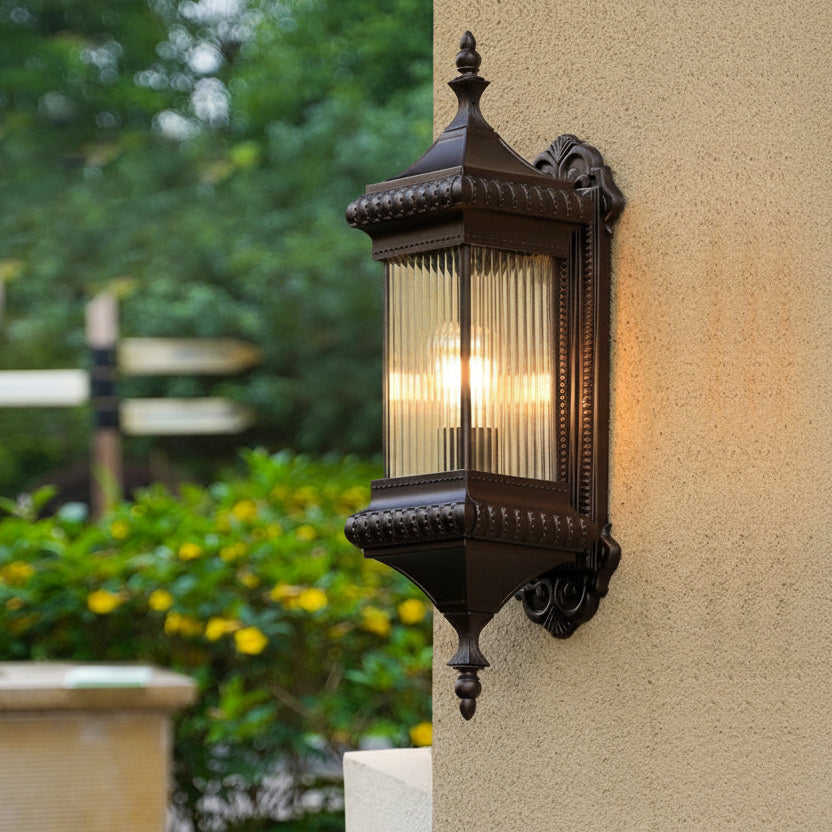 Farol de pared exterior Jaldora – encendido junto a un jardín