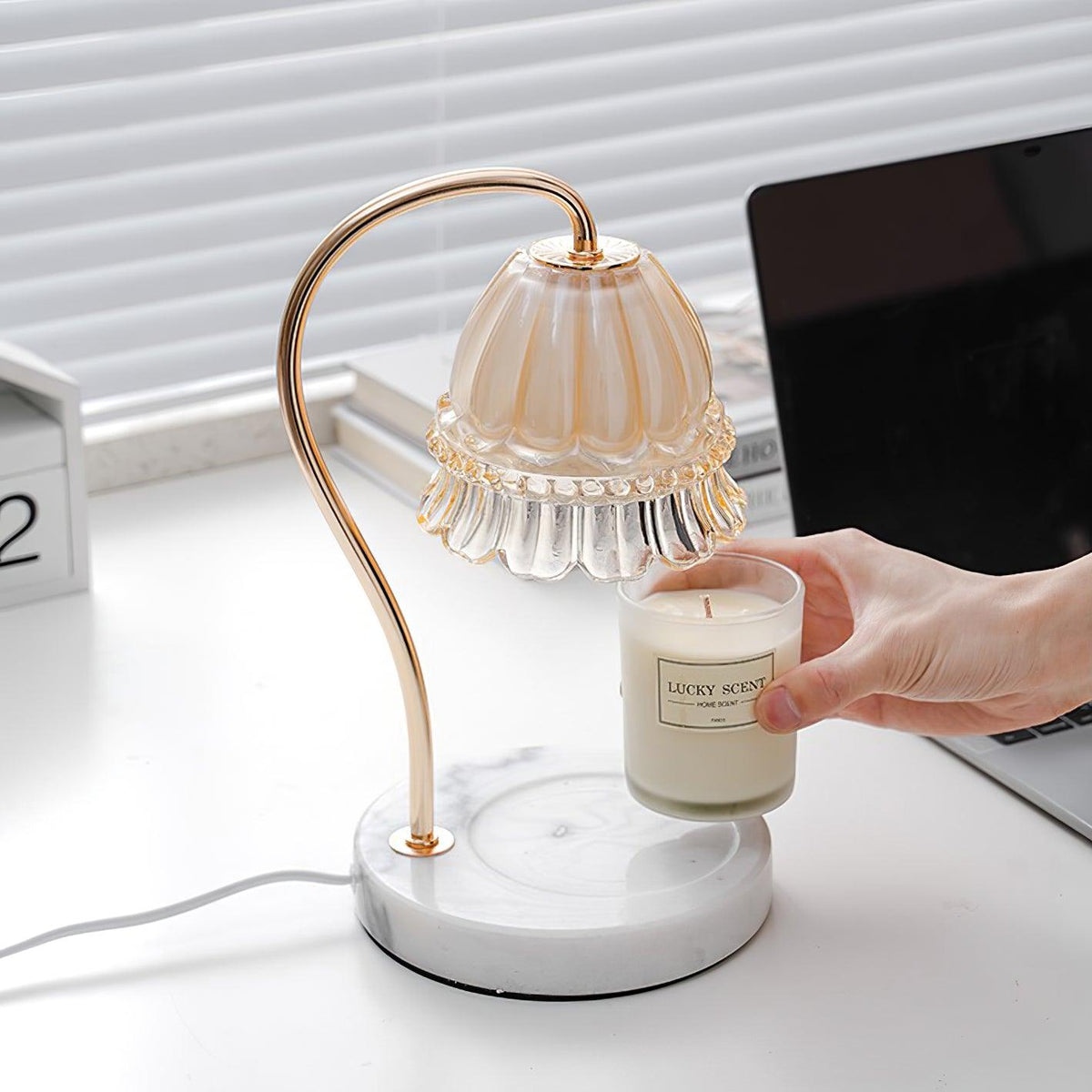 Lámpara de mesa calientavelas de cristal y mármol Miela sobre un escritorio junto a una vela aromática – imagen 3