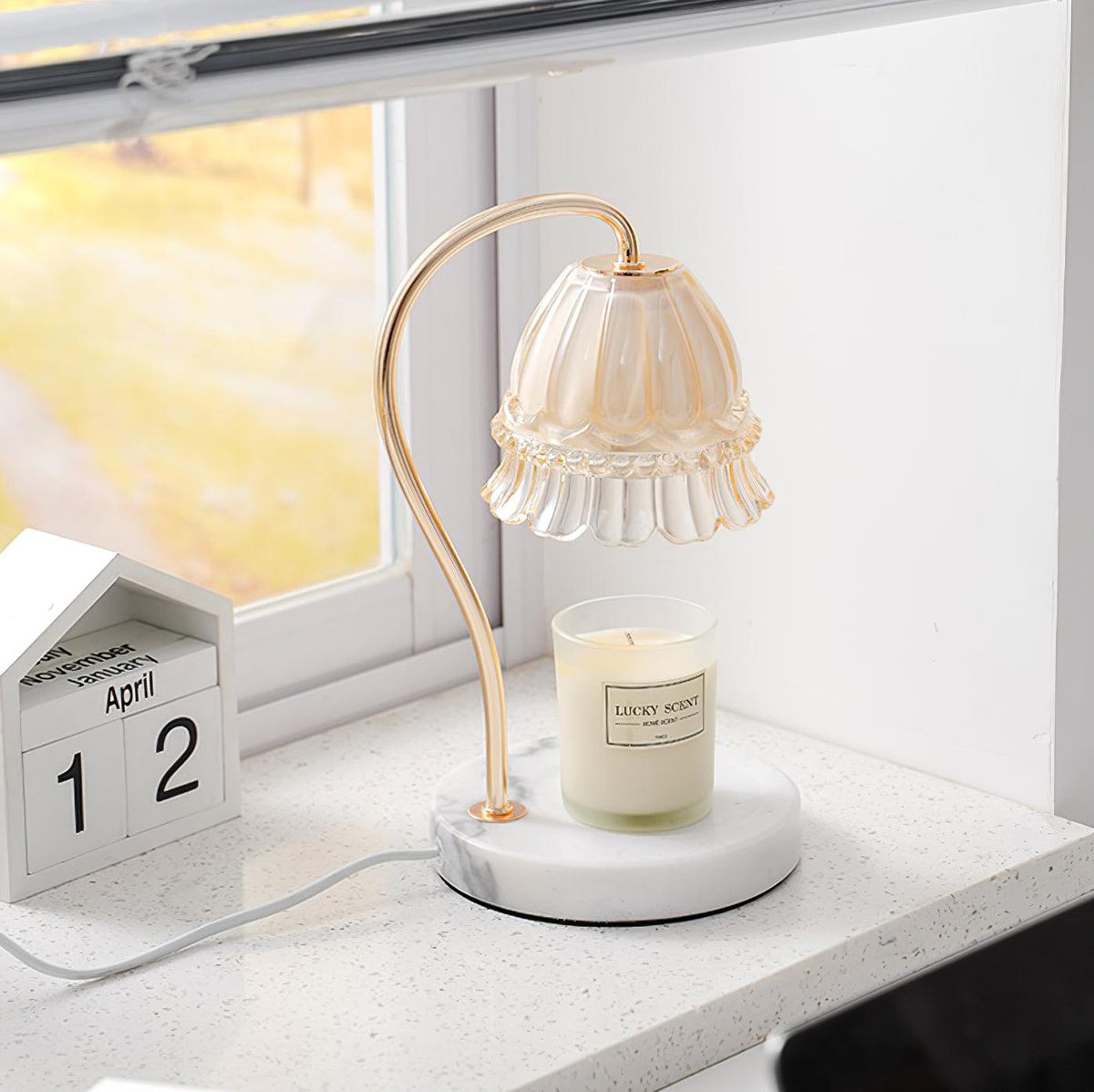 Lámpara de mesa calientavelas de cristal y mármol Miela sobre un escritorio junto a una vela aromática – imagen 8