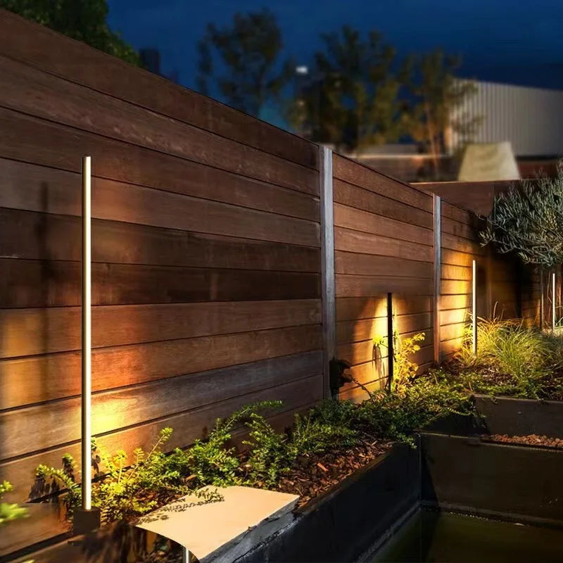 Baliza LED de jardín Mivara – junto a una valla de madera