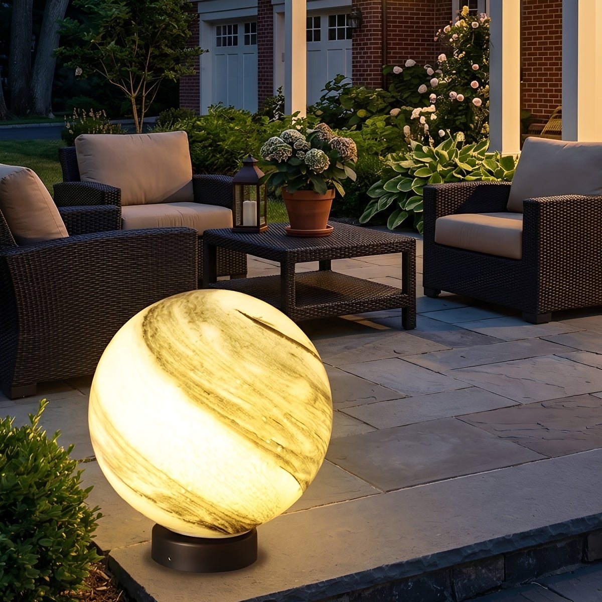 Lámpara de pilar exterior Nuzia – esfera ámbar encendida en una terraza