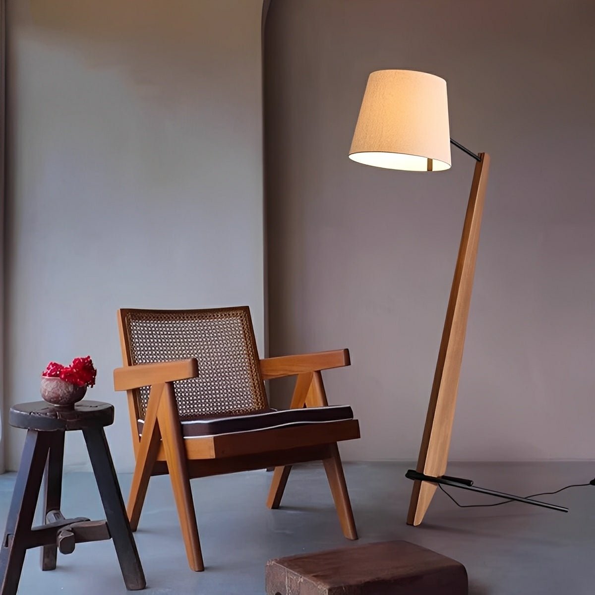 Lámpara de pie inclinada de madera Talunda – en nogal junto a un sillón