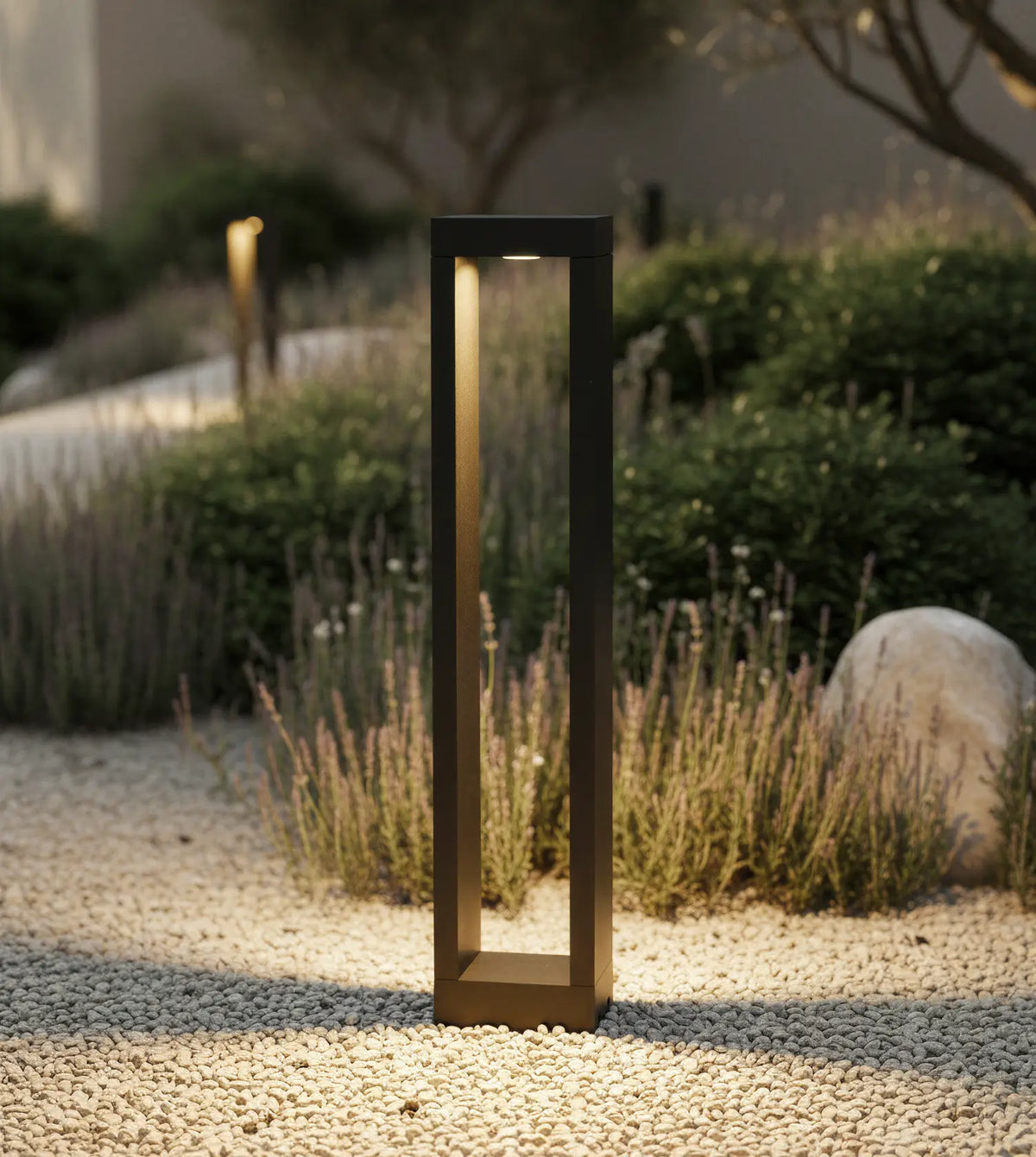 Baliza de jardín LED Nadira – encendida junto a un camino de grava