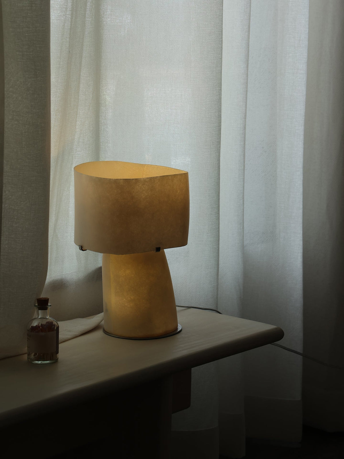 Lámpara de mesa escultural de fibra de vidrio Nevola sobre una mesa auxiliar – imagen 15