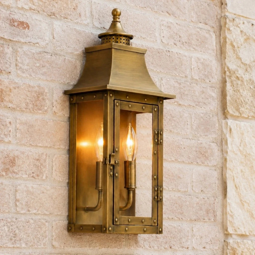 Farol de pared exterior Ocandia – en latón envejecido sobre muro de piedra