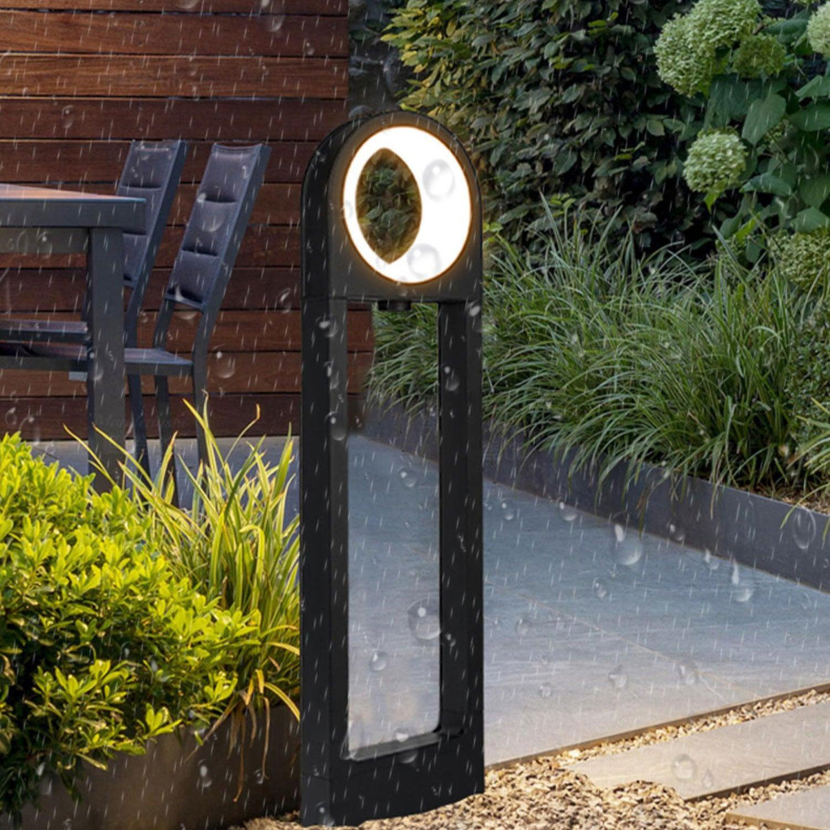 Baliza de jardín LED Oliano – bajo la lluvia junto a un camino