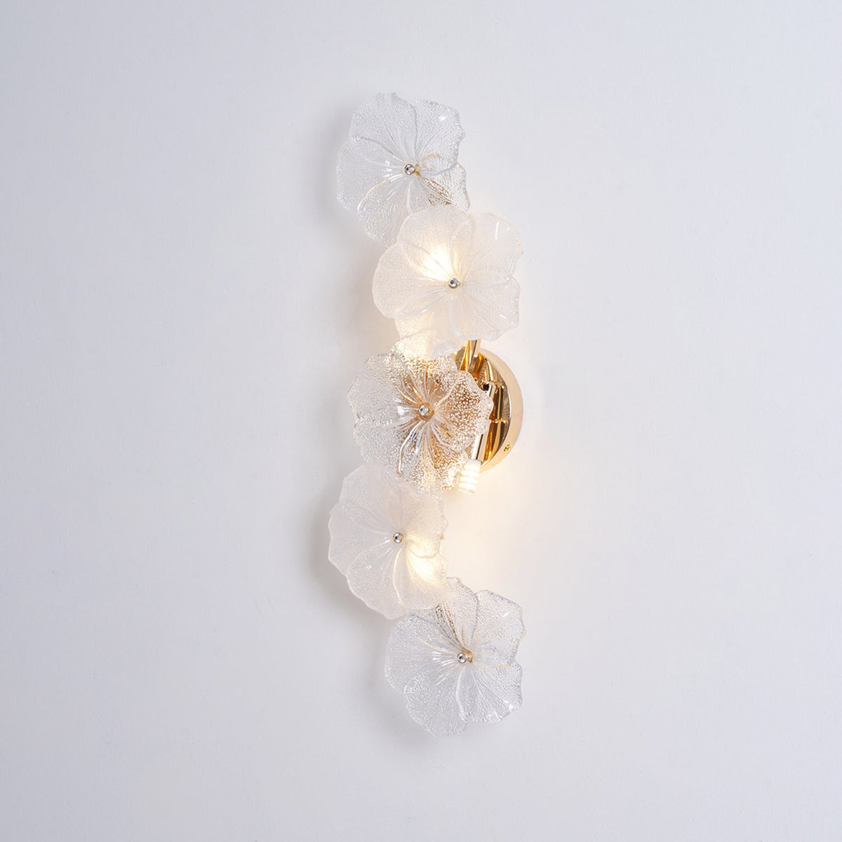 Aplique de pared con flores de cristal Pomelia – encendido sobre pared clara