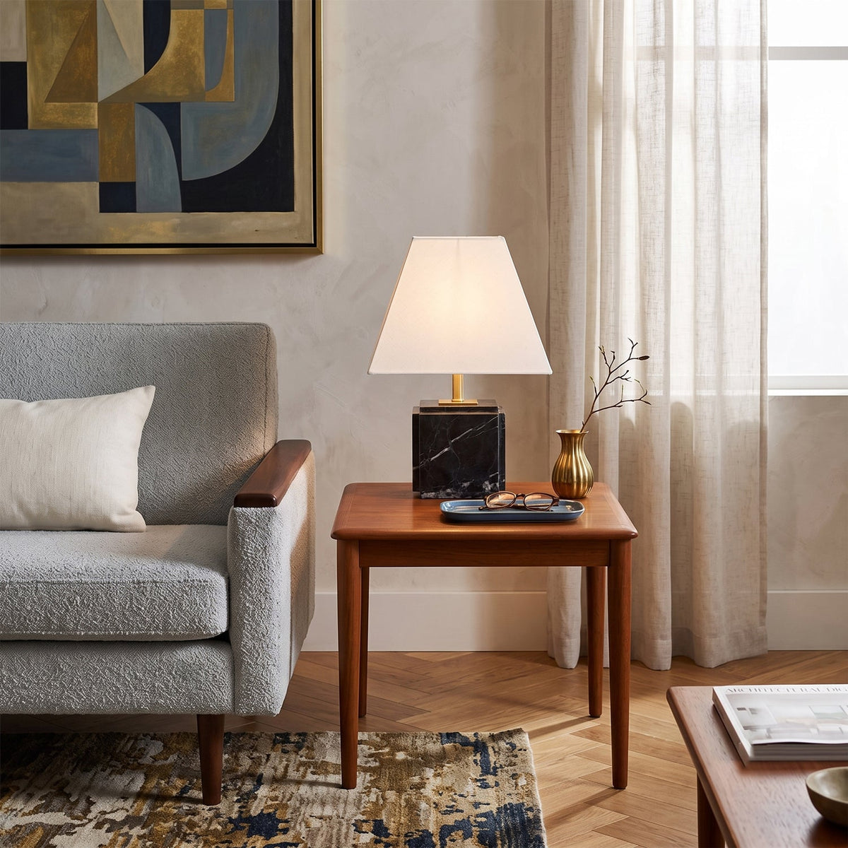 Lámpara de mesa de mármol Quadrela – con base negra junto a un sillón