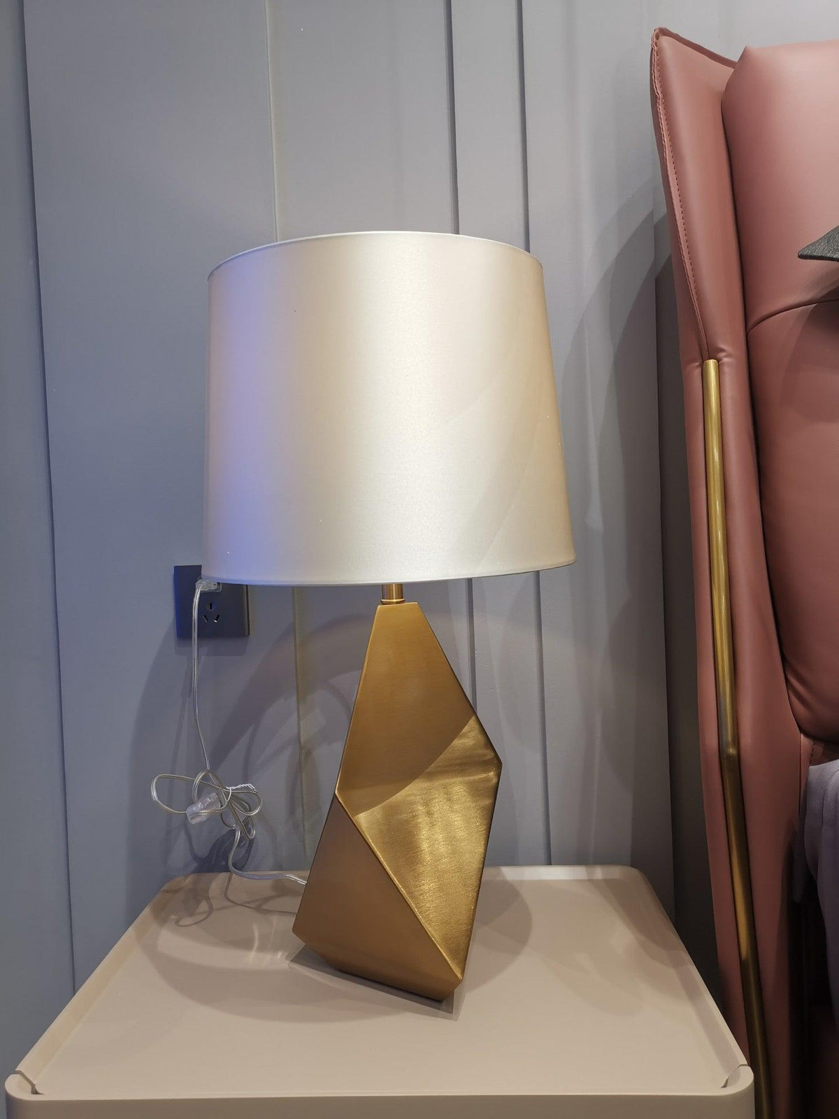 Lámpara de mesa dorada Quilata – en una mesita de noche