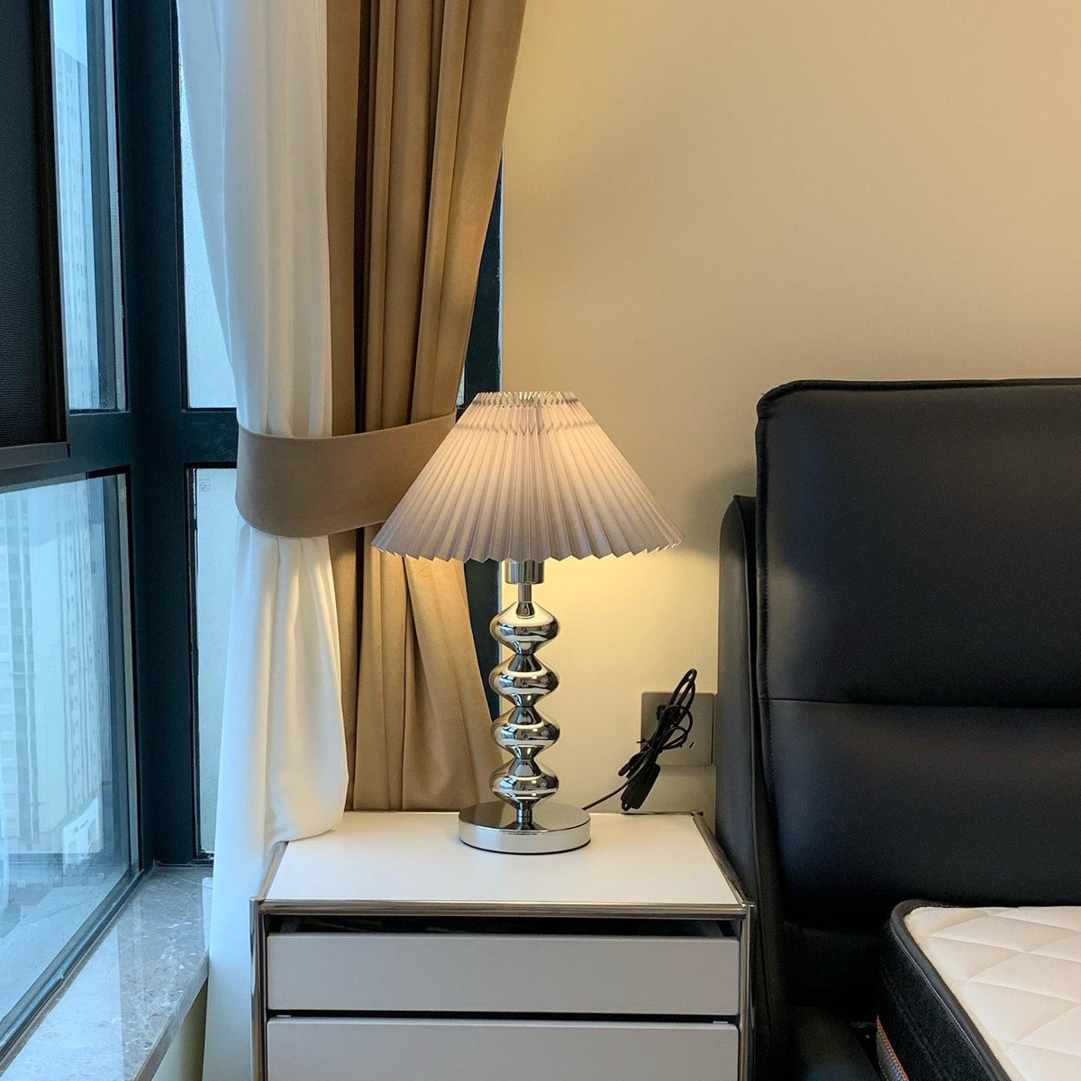 Lámpara de mesa plisada Quisela sobre una mesita de noche – imagen 22