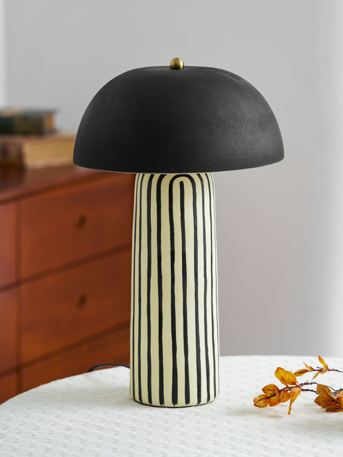 Lámpara de mesa de cerámica a rayas Rayola – junto a una cómoda de madera