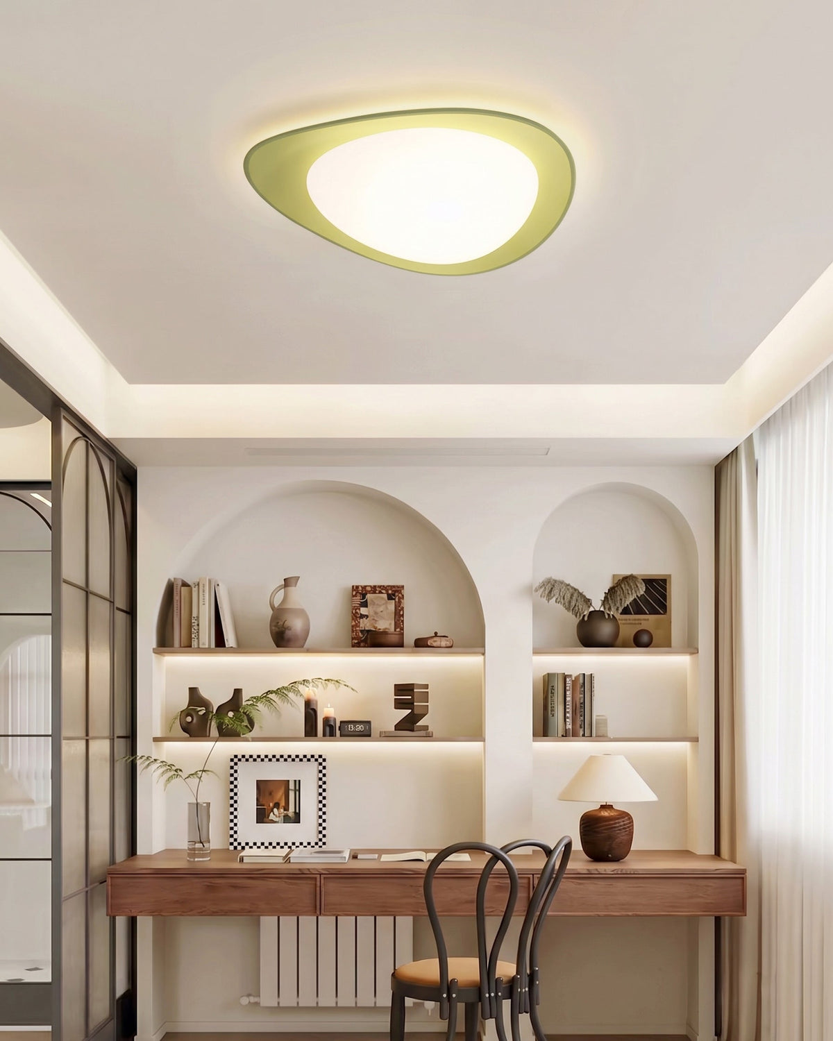Plafón LED en forma de canto rodado Cantela – con aro verde sobre un escritorio
