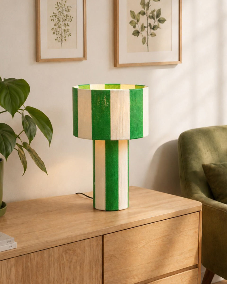 Lámpara de mesa a rayas Rayuna – sobre un aparador junto a plantas