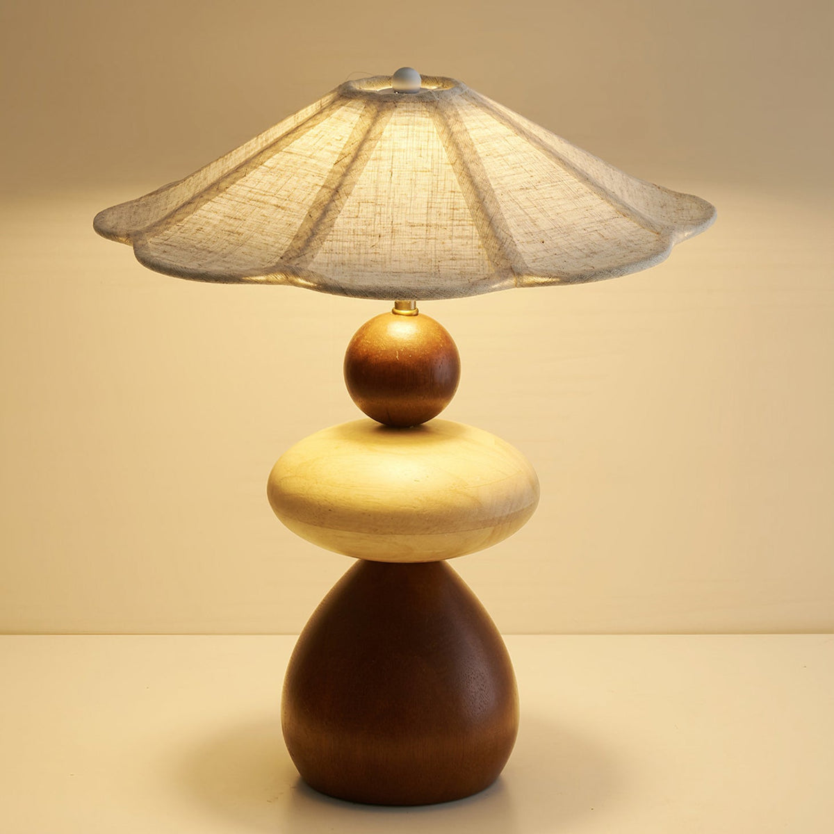 Lámpara de mesa de madera Rimela – encendida en una mesita de noche