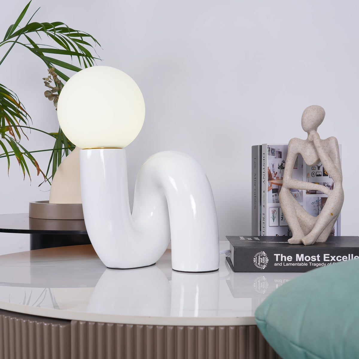 Lámpara de mesa escultural Rizeta – blanca en una mesa auxiliar