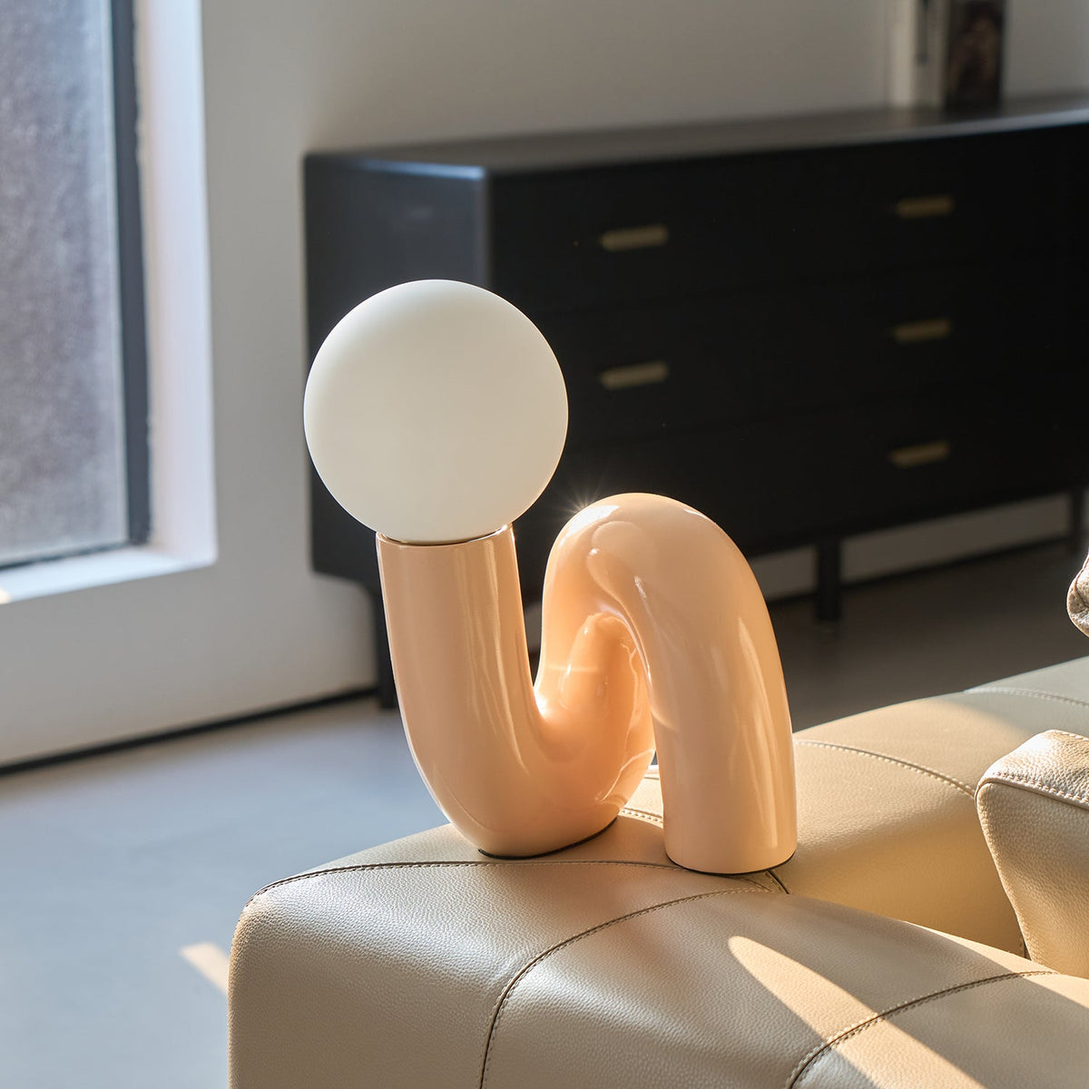 Lámpara de mesa escultural Rizeta – rosa encendida sobre una cómoda