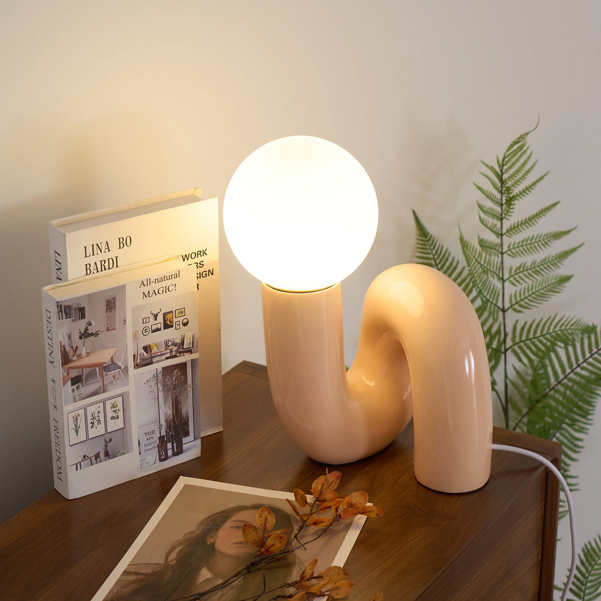 Lámpara de mesa escultural Rizeta – rosa en un aparador de madera