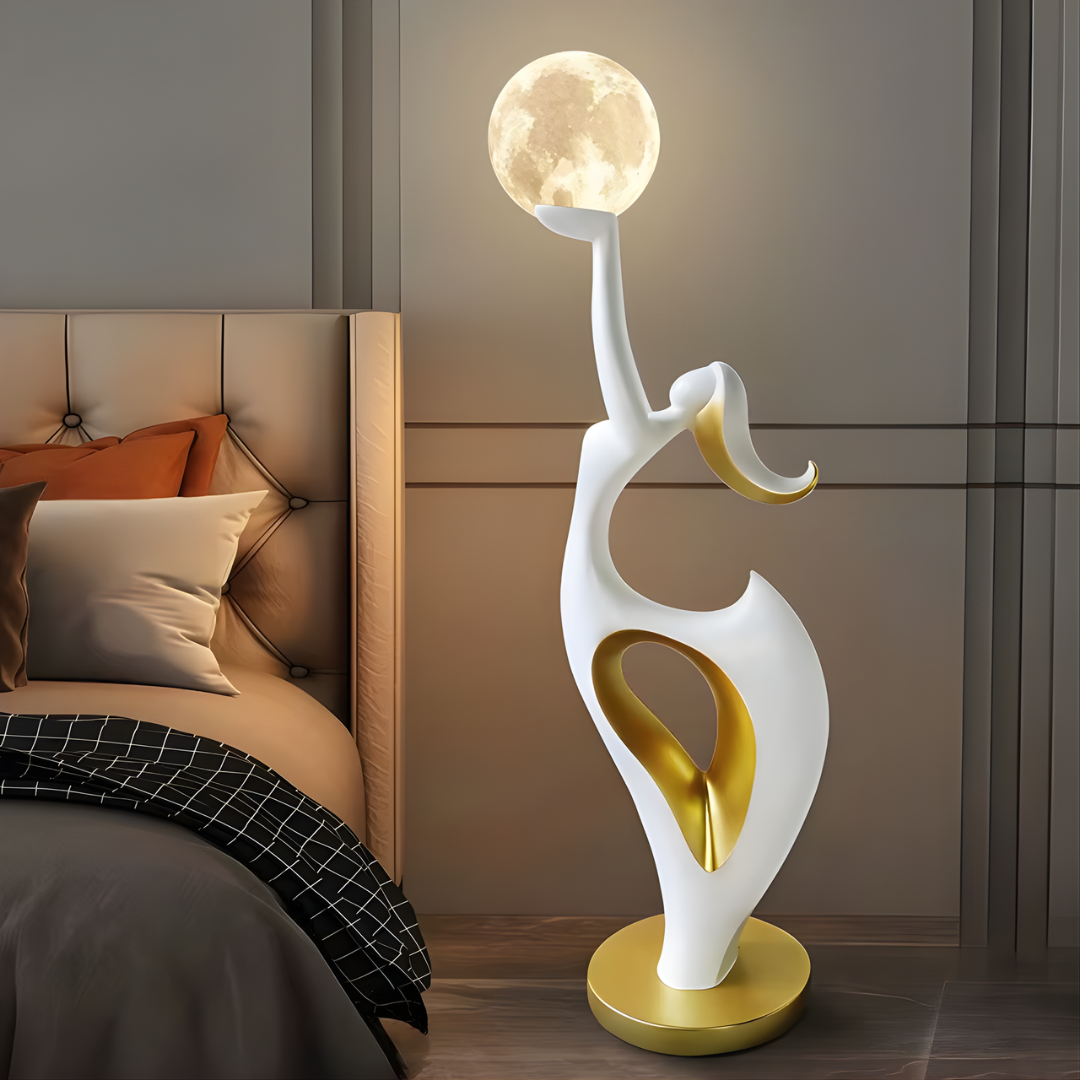 Lámpara de pie escultura Rolunia – en blanco y dorado junto a una cama
